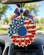 Handmade American flag sunflower car freshie, a patriotic red white and blue aroma bead air freshener shaped like a sunflower, hanging from a car rearview mirror.