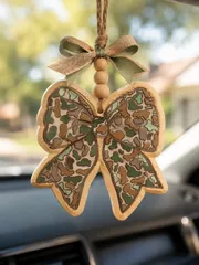 Handmade camouflage bow car freshie air freshener in camo print, a country western hunting style scented aroma bead accessory hanging for cars and trucks.