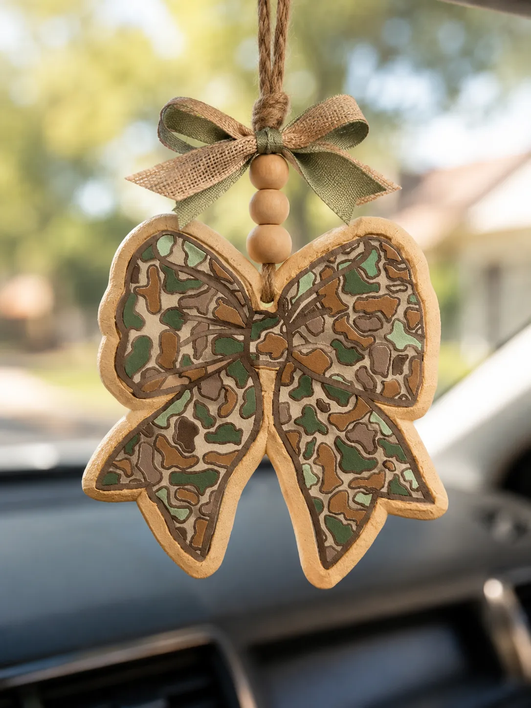 Handmade camouflage bow car freshie air freshener in camo print, a country western hunting style scented aroma bead accessory hanging for cars and trucks.