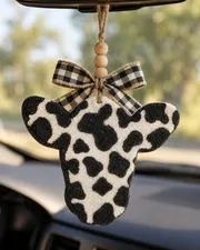 Handmade cow print cow head freshie, a western country scented aroma bead car air freshener hanging from a rear-view mirror.
