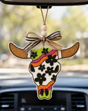 Handmade western swirl daisy bull skull freshie car air freshener made of scented aroma beads with a daisy flower and longhorn cow skull design hanging in a car.