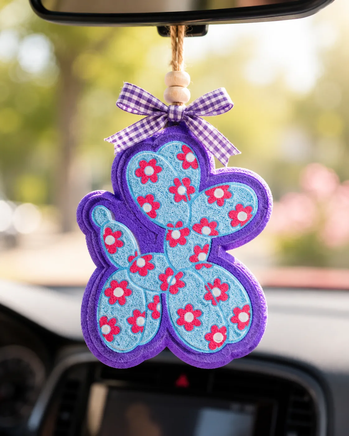 Handmade flower balloon animal car freshie shaped like a floral balloon dog aroma bead air freshener hanging from a car rearview mirror.