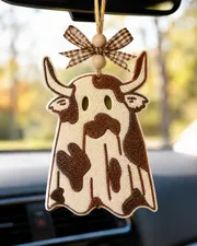 Handmade ghost cow car freshie, a cute cow-shaped scented air freshener covered in a white Halloween ghost sheet, hanging in a car for cow lovers and western fall decor.