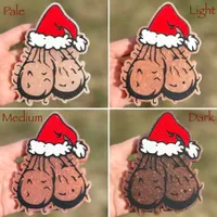 Christmas car freshie shaped like a cartoon Santa sack with a red and white Santa hat and a smiling face, shown in four skin-tone variations labeled Pale, Light, Medium, and Dark, each held in a hand outdoors over grass.